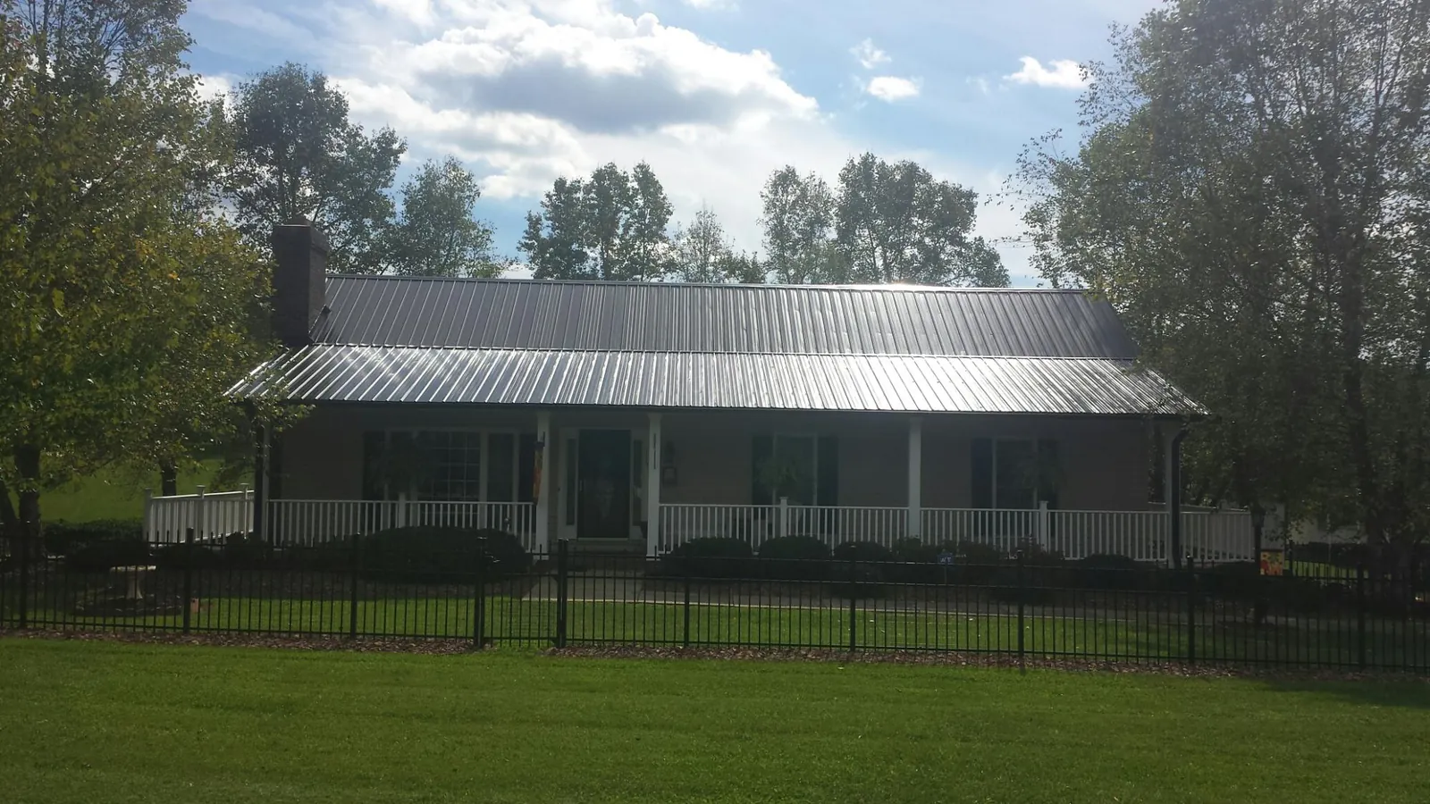 Gray metal roof on a brick ranch with a full width front porch — Gutter Guard Installation work by our crew in Toone