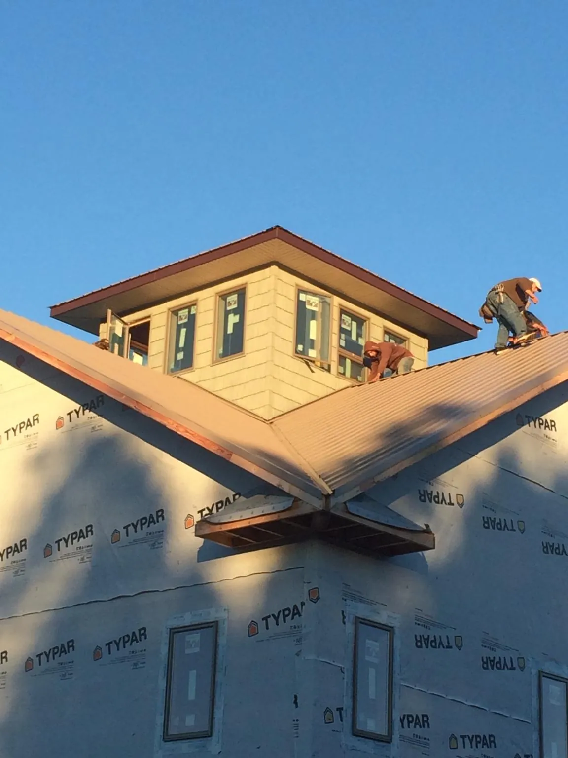Roofers working around a rooftop cupola on a new metal roof at sunset — Roof Waterproofing in Toone by Roofing Brothers